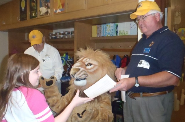 Lions Chuck Temple and Bill Ellis hand out dictionaries at Bailey Elementary School, with the assistance of Chester the Lion (a.k.a. Lion Robin Smith).